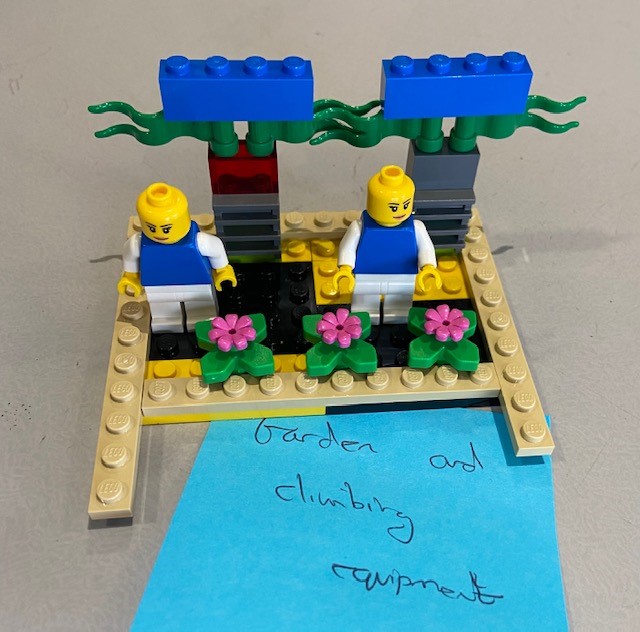 A Lego garden built by a young person. Two Lego people are standing in the garden.