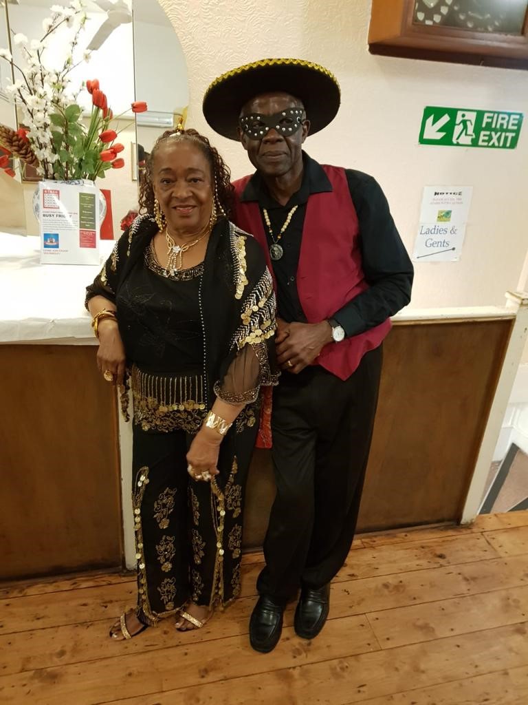 Foster carers Lorina and Dervin stand side by side dressed up for a party. 